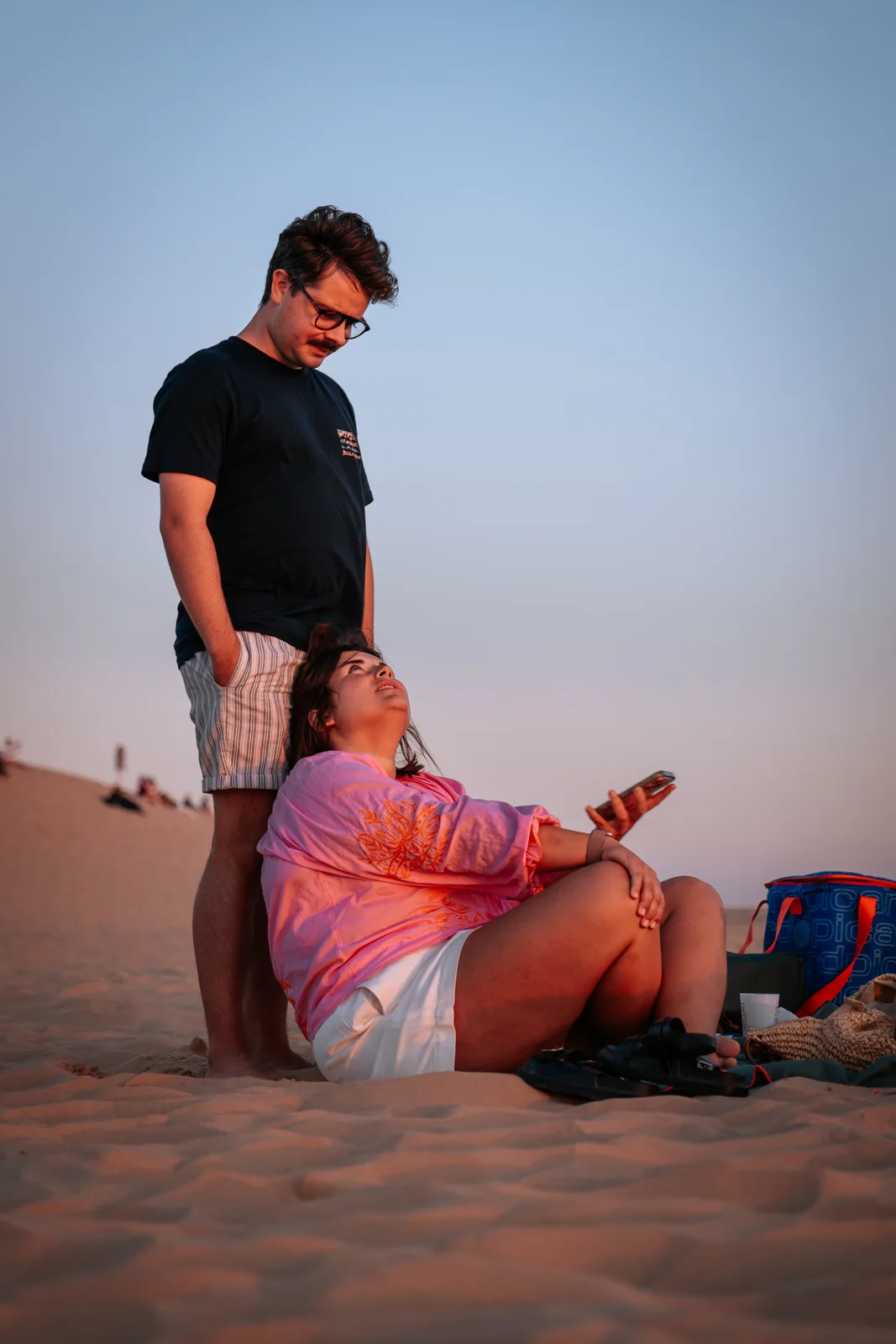 Un couple profite d’un instant calme dans le sable à la lumière du soir.