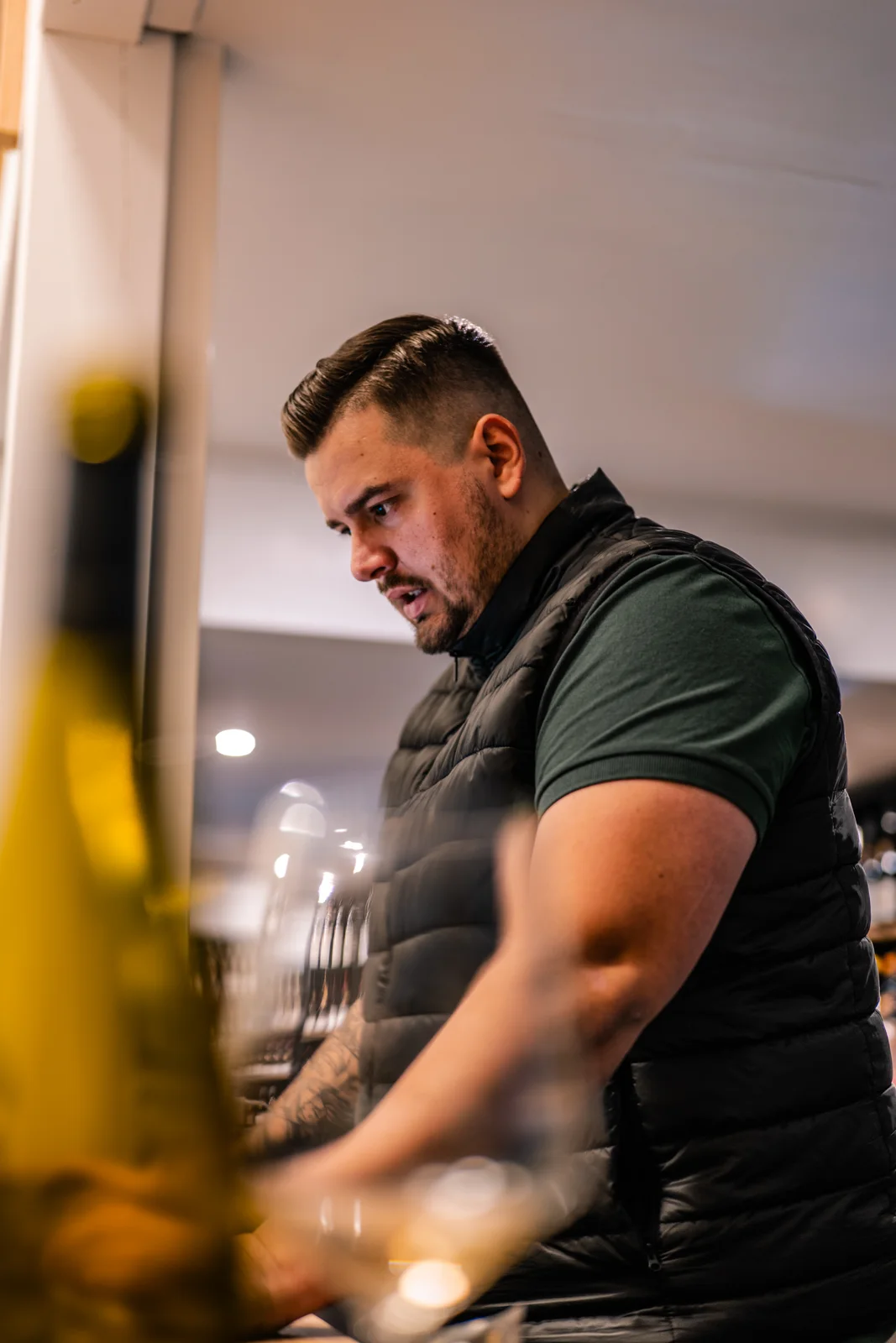 Un caviste au travail derrière son comptoir, dans une lumière chaleureuse.