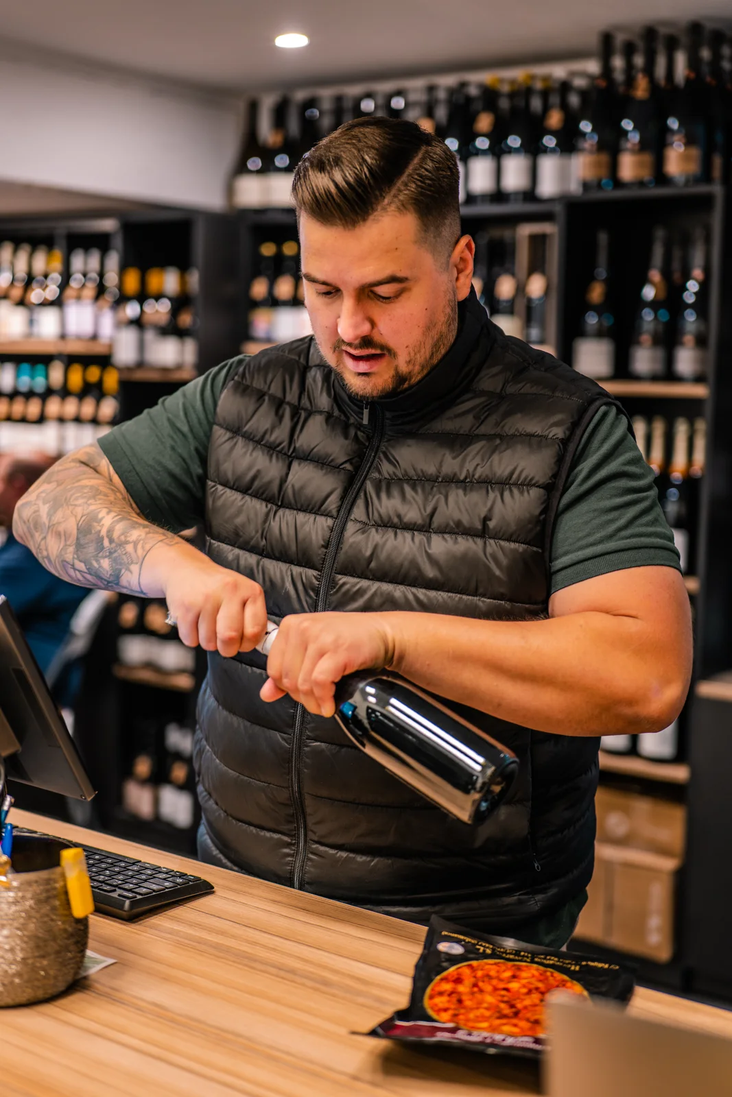 Un professionnel ouvre soigneusement une bouteille de vin dans sa boutique.