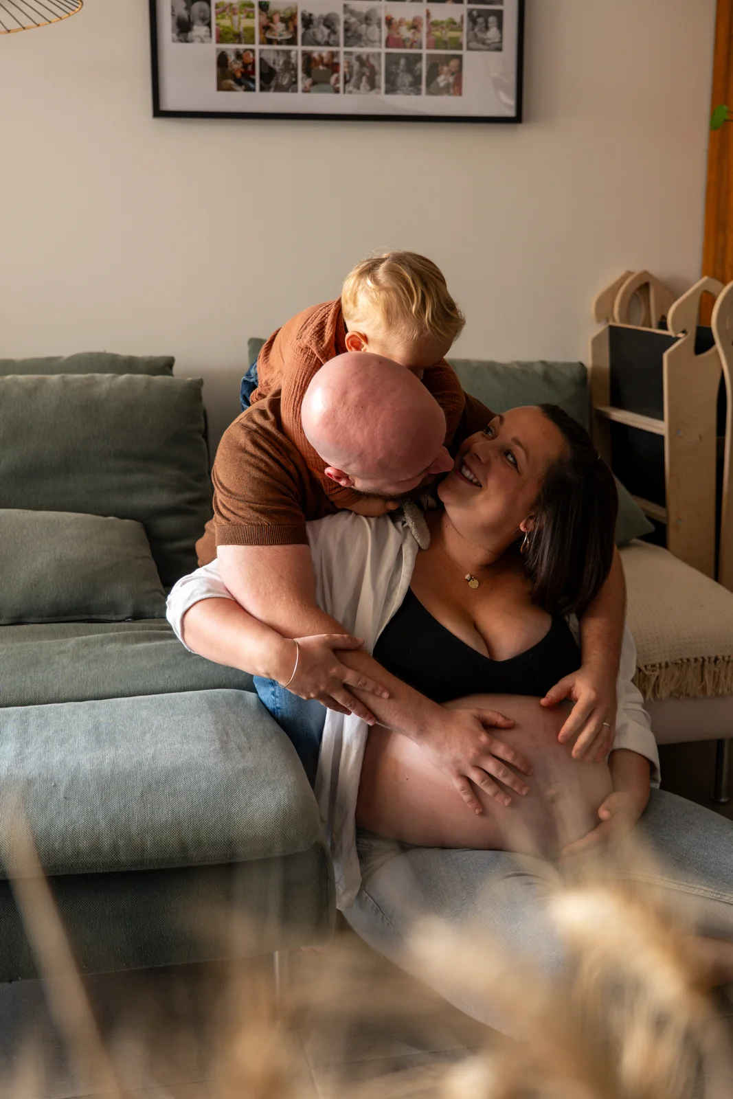 Une famille réunie à la maison enlace la future mère assise au sol.