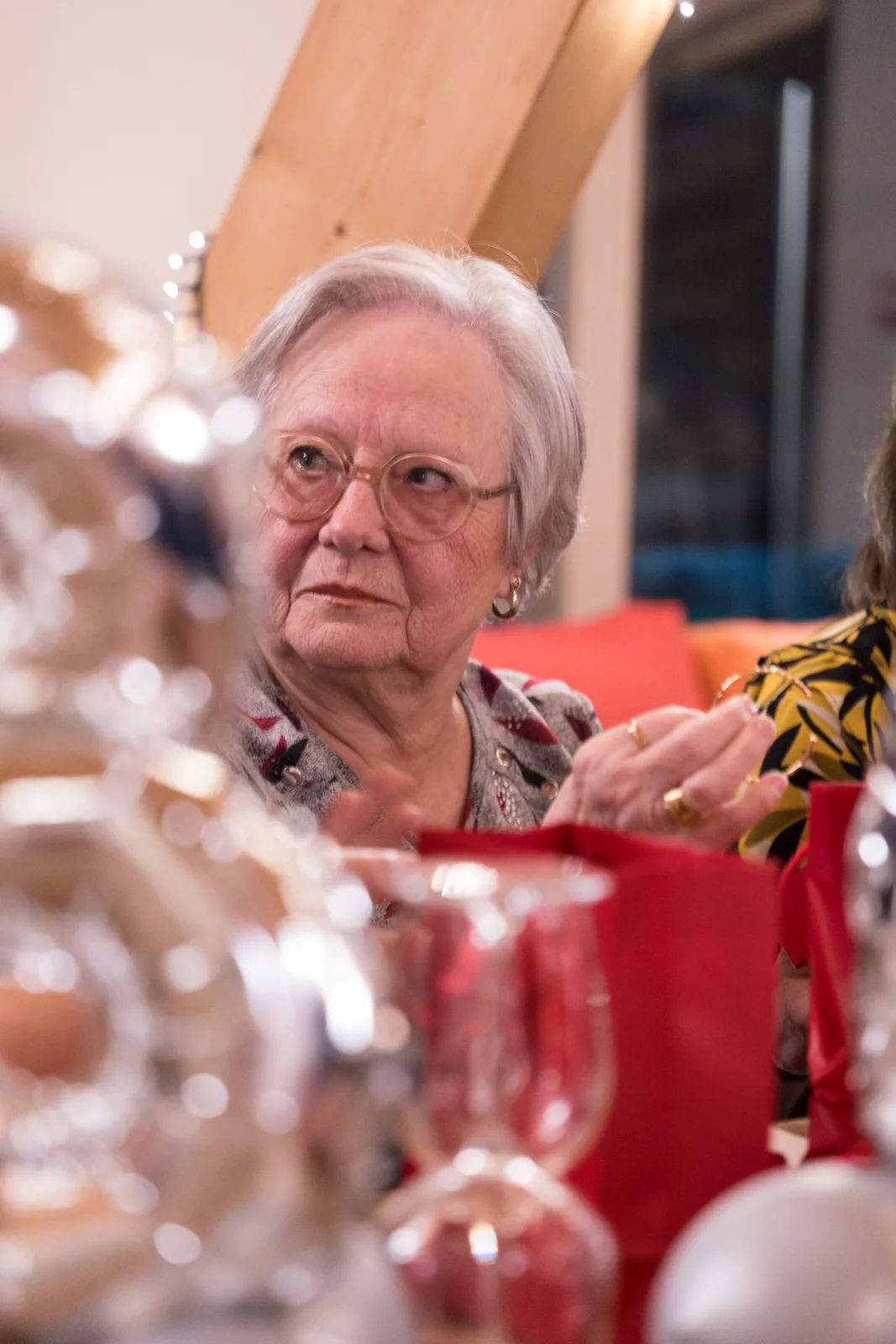 Une grand-mère observe ses proches avec émotion pendant une réunion de famille.