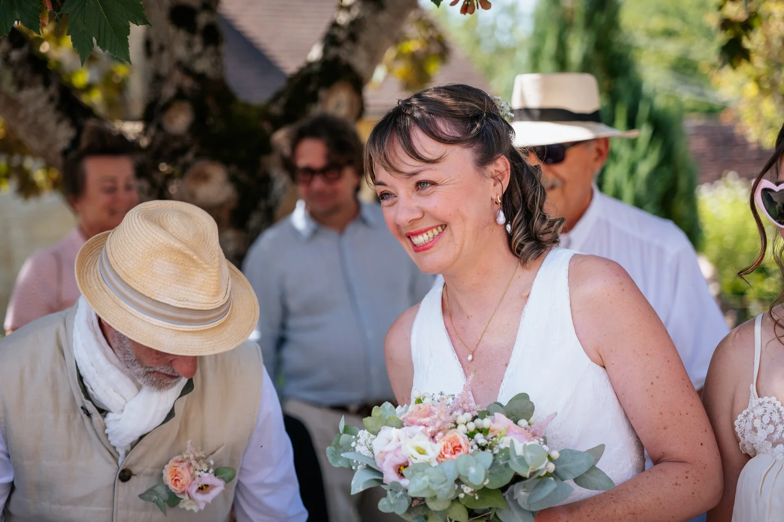 Une mariée sourit, son bouquet aux couleurs douces dans les bras.