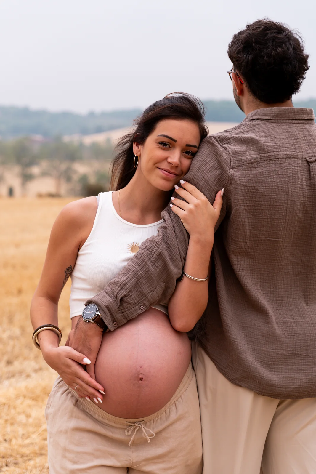 Une future mère se blottit contre son compagnon, le ventre découvert.