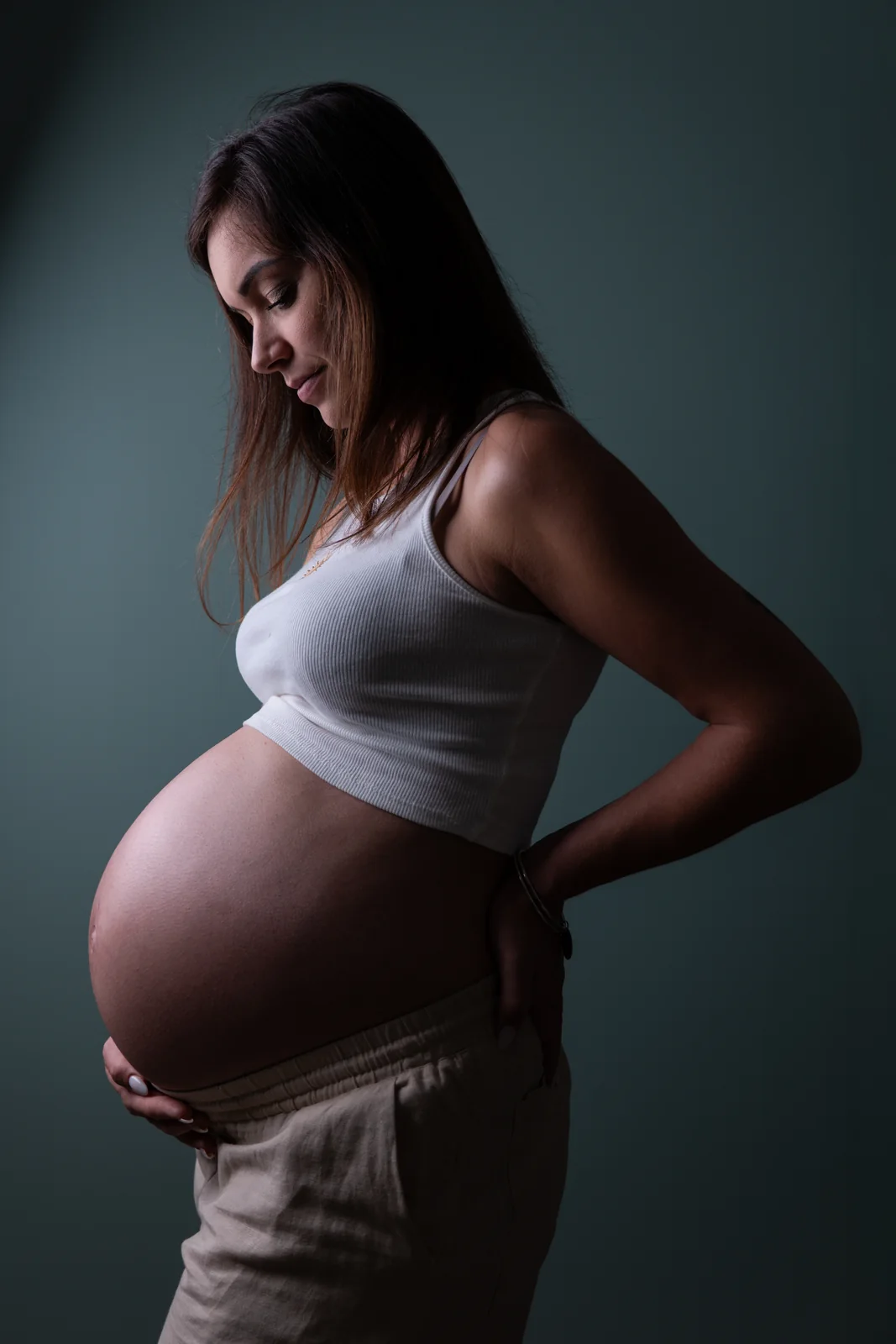 Le profil d’une future mère et de son ventre est sculpté par une lumière douce en studio.