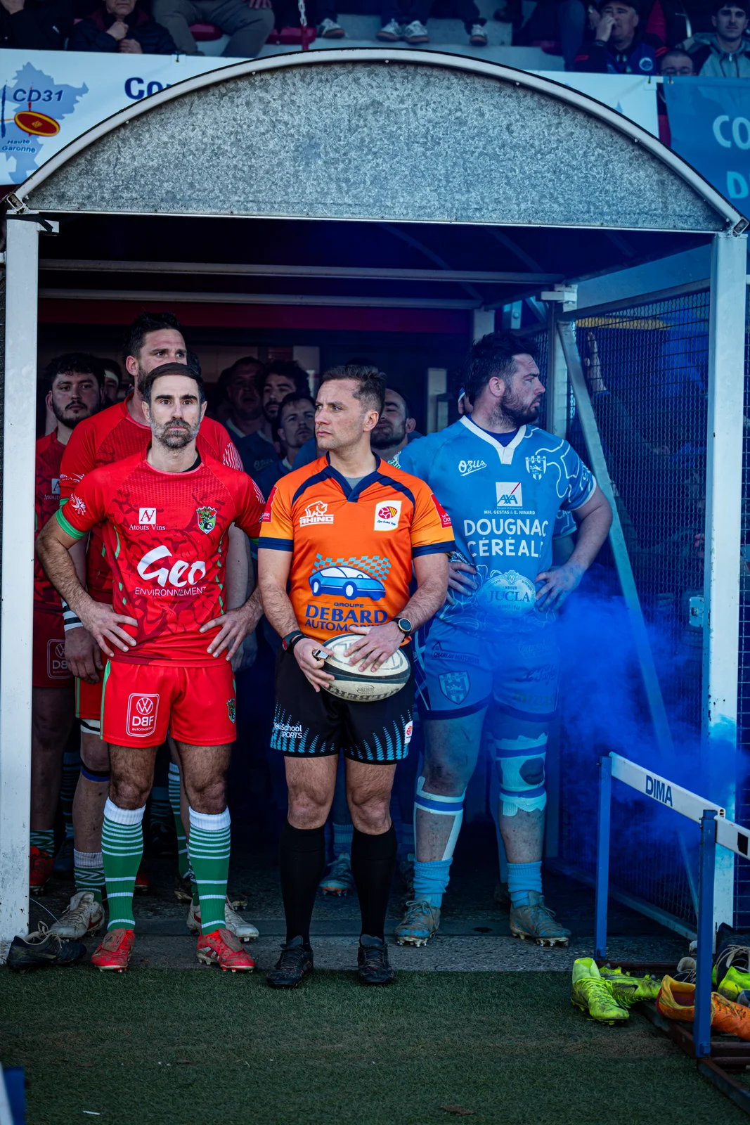 Des joueurs et l’arbitre attendent dans le tunnel au milieu d’une fumée bleue avant d’entrer sur le terrain.