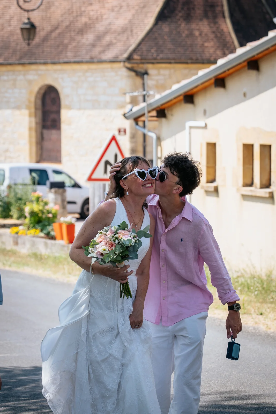 Les mariées s’embrassent au soleil avec des lunettes en forme de cœur.
