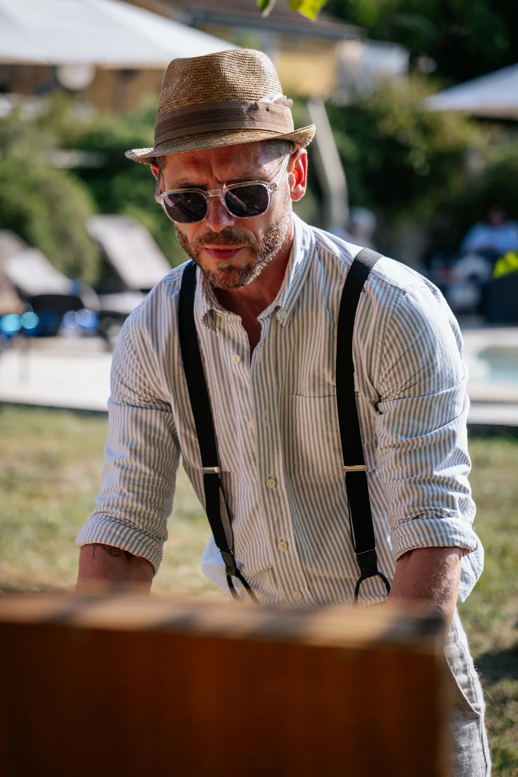 Un invité en bretelles profite du cocktail dans la lumière d’été.