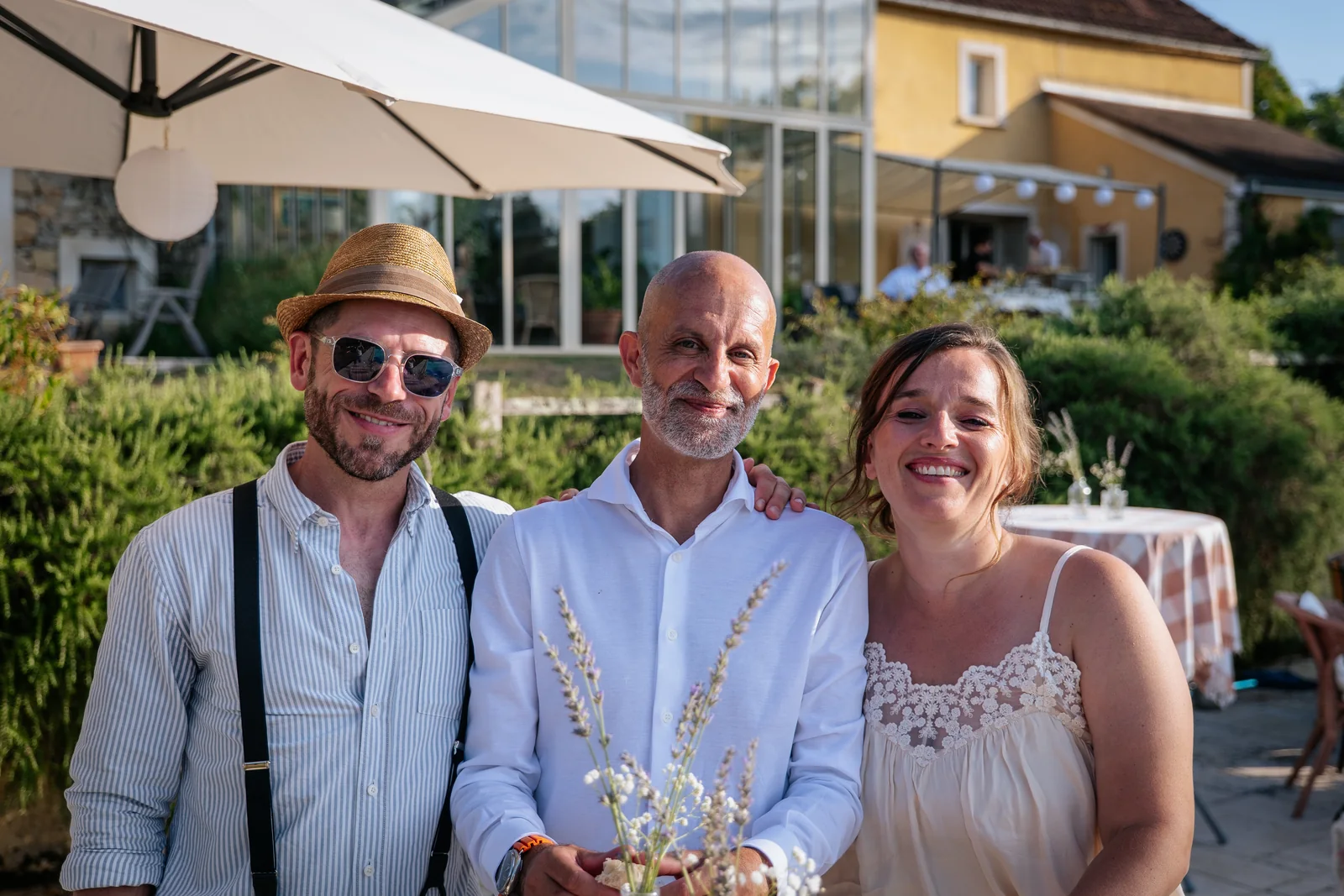 Trois proches sourient ensemble à la fin d’une journée de mariage.